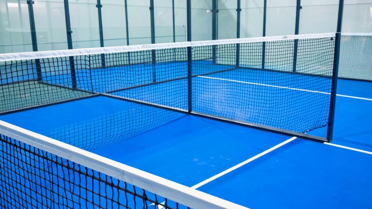 Netz und Spielfeldlinien eines leeren blauen Padel-Courts aus der Nähe