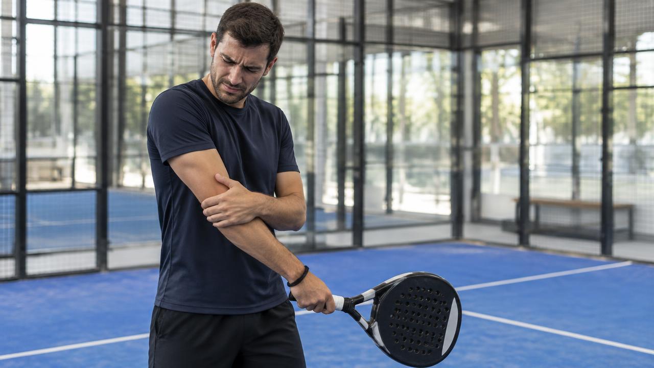 Padel-Spieler auf dem Platz hält sich den schmerzenden Ellenbogen
